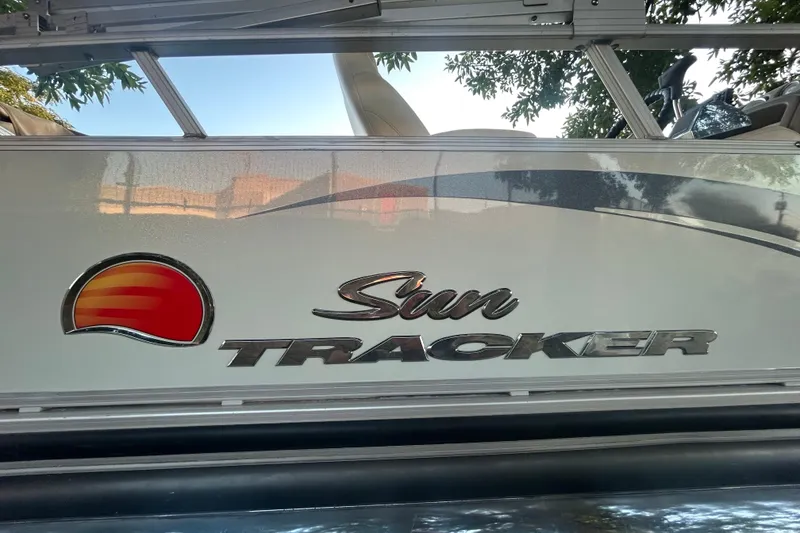 Slide: The Image of 2011 SUNTRACKER PARTY BARGE 22 REGENCY EDITION with Mercury outboard motor, parked under trees. - 4