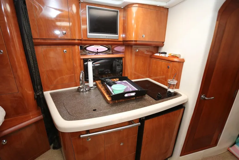 Slide: The Image of 2005 Four Winns 348 Vista yacht interior with kitchenette, featuring wood cabinetry and modern appliances. - 38