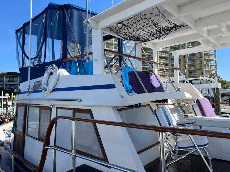 Slide: The Image of 1983 Lindmark 39 Trawler with blue canopy, docked near modern buildings. - 10