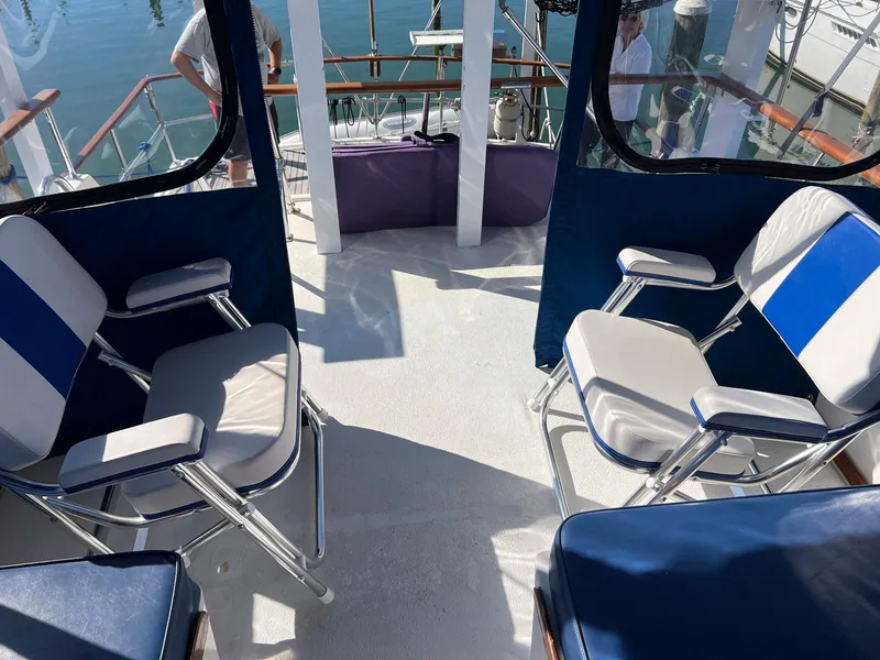 Slide: The Image of 1983 Lindmark 39 Trawler interior with blue and white seating, docked at marina. - 14