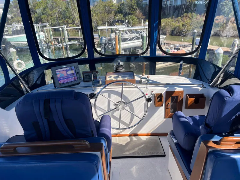 Slide: The Image of 1983 Lindmark 39 Trawler helm with blue seats, steering wheel, and navigation equipment. - 18