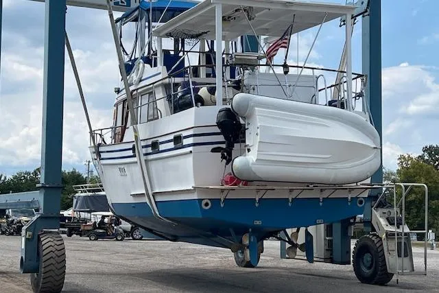 Slide: The Image of 1983 Lindmark 39 Trawler on a lift with attached dinghy, ready for maintenance. - 2