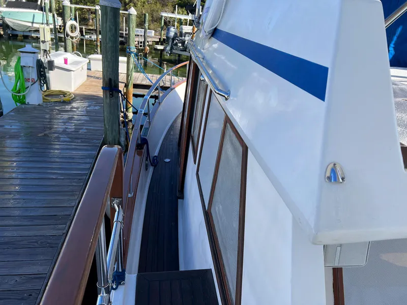 Slide: The Image of 1983 Lindmark 39 Trawler docked, showcasing side deck and cabin details. - 24