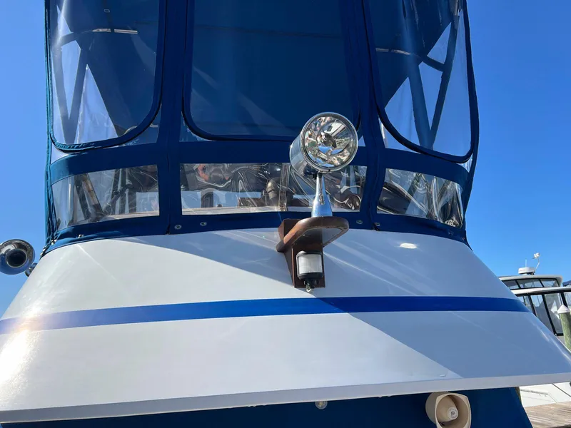 Slide: The Image of 1983 Lindmark 39 Trawler with blue canopy and spotlight, docked under clear sky. - 32