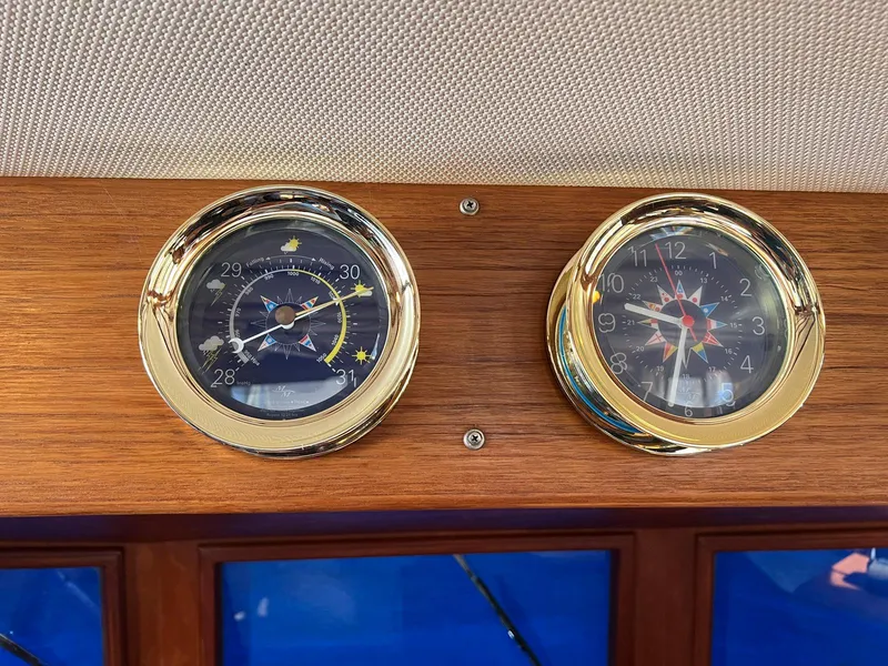 Slide: The Image of Nautical instruments on 1983 Lindmark 39 Trawler, featuring barometer and clock with wooden paneling. - 45