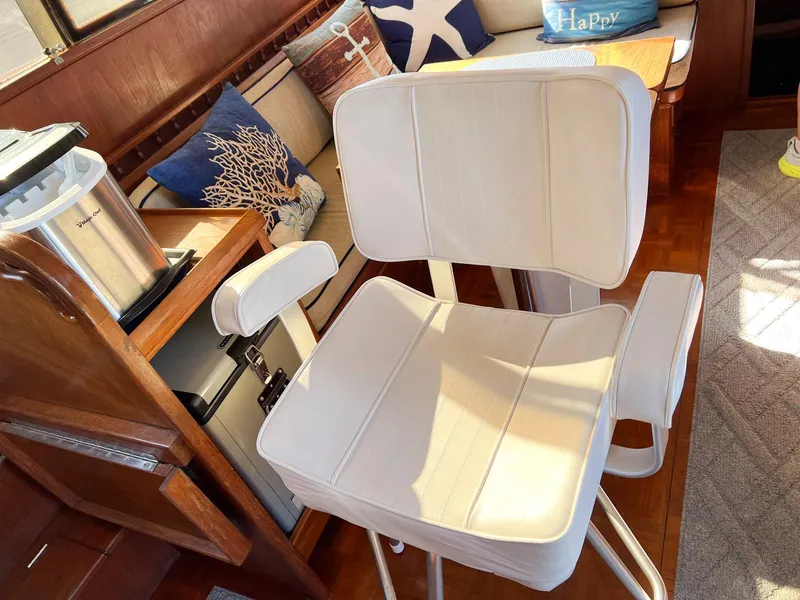 Slide: The Image of White captain's chair in 1983 Lindmark 39 Trawler interior, with nautical-themed cushions. - 48