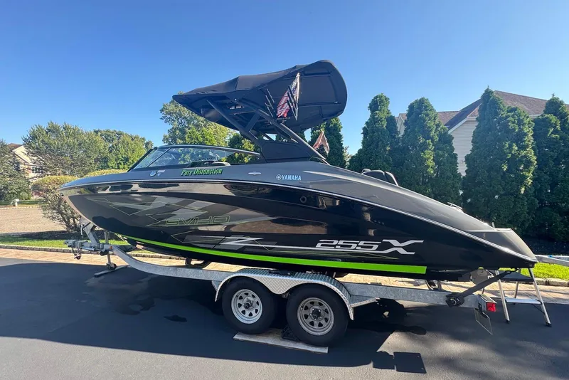 The Image of 2021 Yamaha Boats 255XD on trailer, sleek black design, parked outdoors. - 0