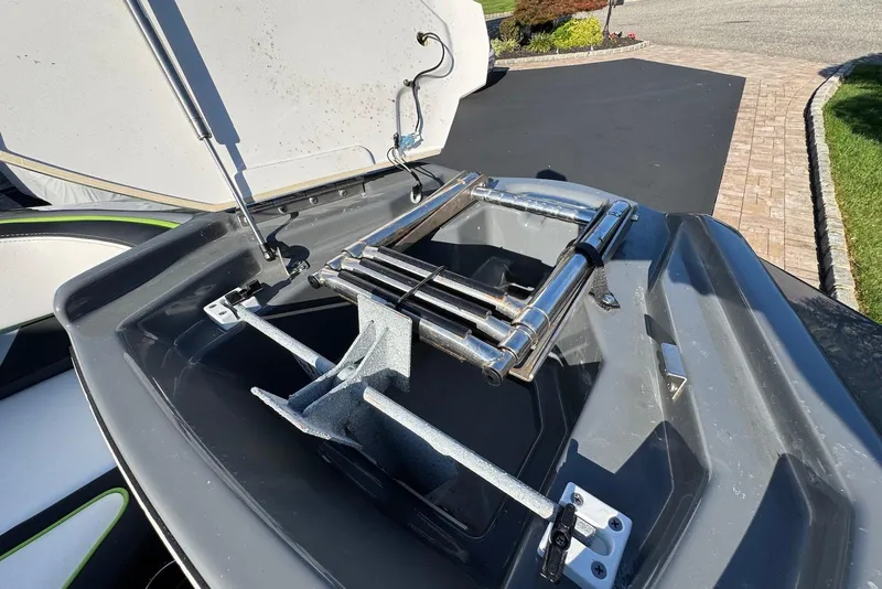 Slide: The Image of 2021 Yamaha Boats 255XD anchor compartment with ladder, open on a sunny day. - 11