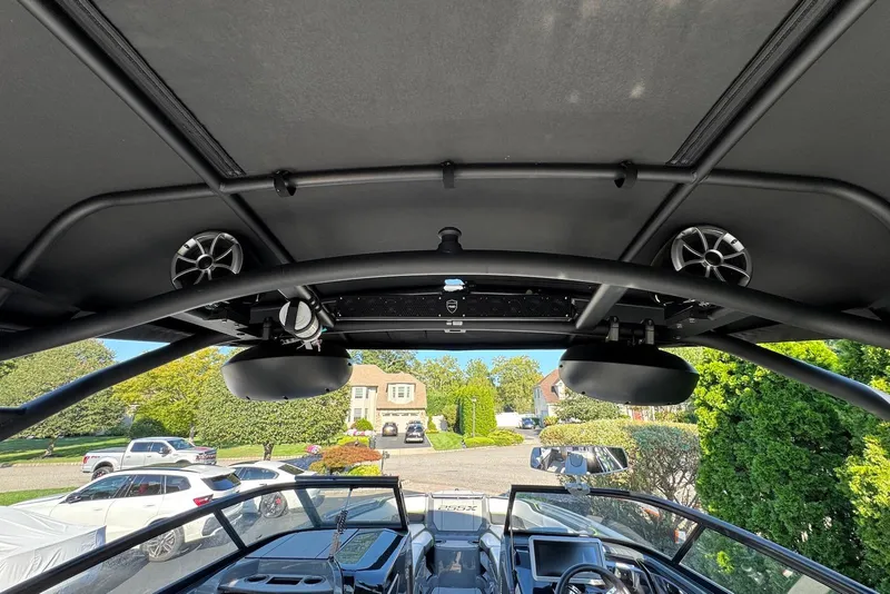 Slide: The Image of 2021 Yamaha Boats 255XD interior view with speakers and dashboard, parked in a residential area. - 23