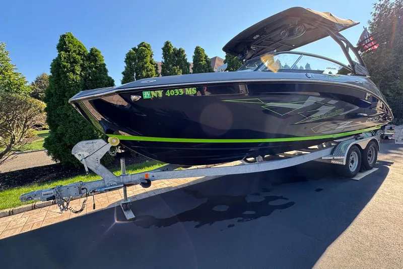 Slide: The Image of 2021 Yamaha Boats 255XD on trailer, sleek design with green accents, parked outdoors. - 3