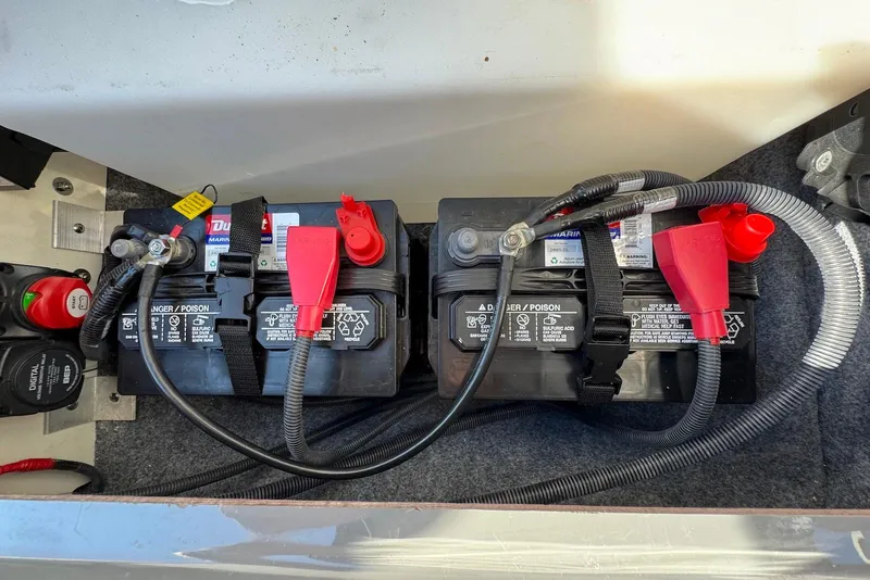 Slide: The Image of Dual marine batteries in a 2021 Yamaha Boats 255XD, secured with straps and connected with cables. - 31
