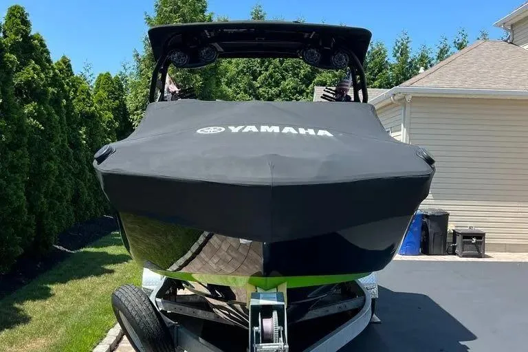Slide: The Image of 2021 Yamaha Boats 255XD covered and parked in a driveway, surrounded by greenery. - 33