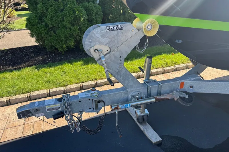 Slide: The Image of Trailer hitch of 2021 Yamaha Boats 255XD, parked on driveway with greenery background. - 35