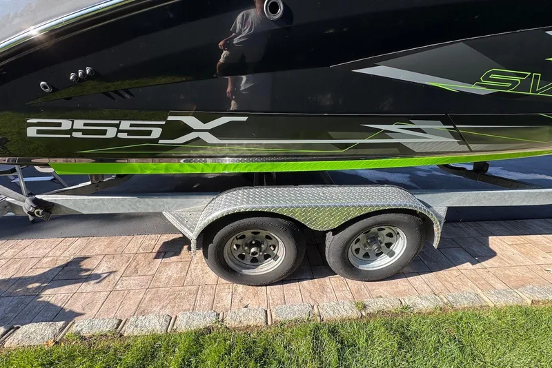 Slide: The Image of 2021 Yamaha Boats 255XD on trailer, featuring sleek black and green design. - 5