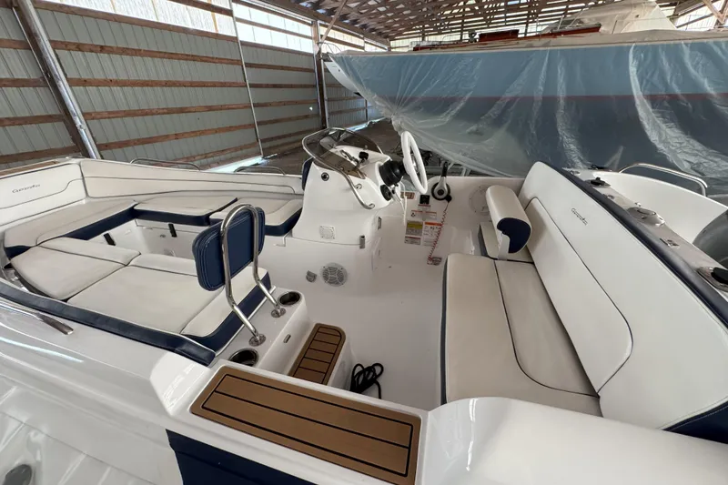 Slide: The Image of 2024 Walker Bay Generation 525 boat interior with white seating and steering console in a storage facility. - 15