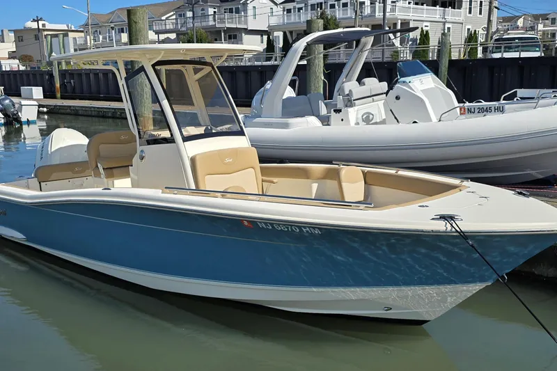 The Image of 2019 Scout 235 XSF boat docked in marina, blue and white exterior. - 0