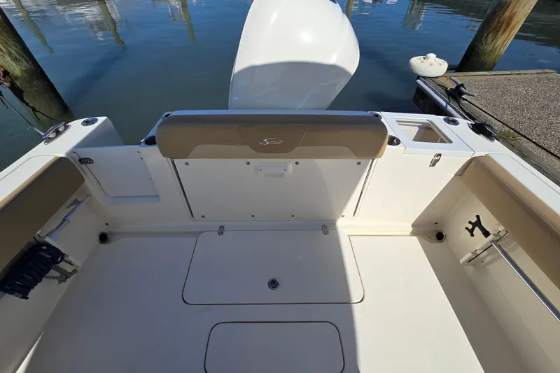 Slide: The Image of 2019 Scout 235 XSF boat interior with seating and storage, docked by the water. - 11