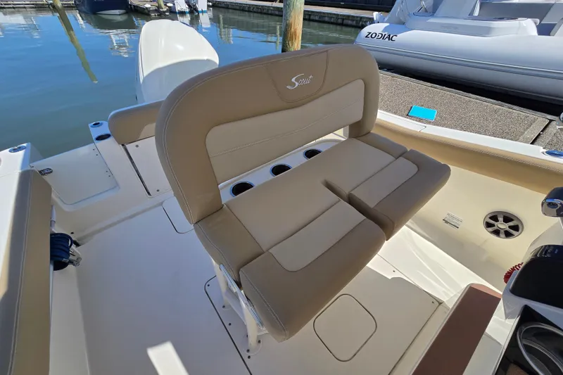 Slide: The Image of 2019 Scout 235 XSF boat interior with beige seating and cup holders at a marina. - 14