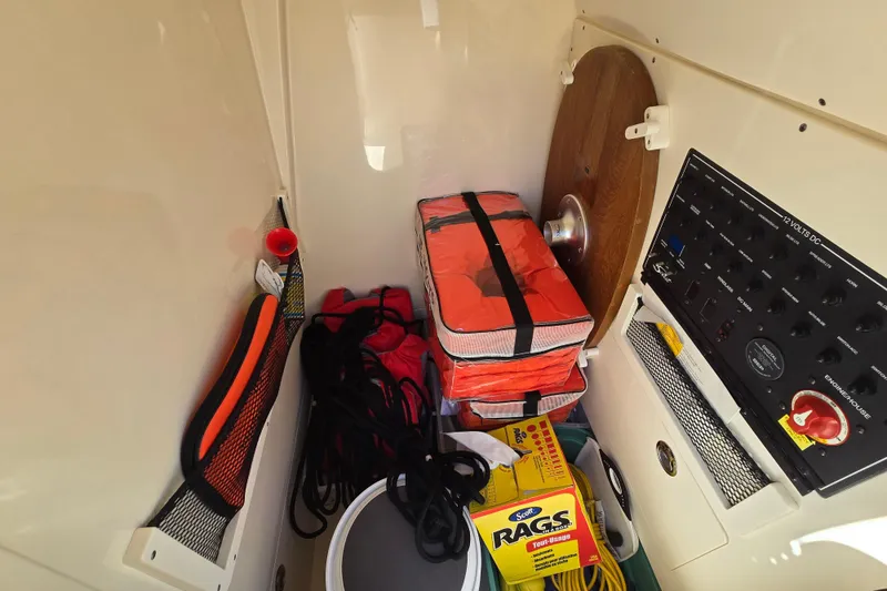 Slide: The Image of Storage compartment of 2019 Scout 235 XSF boat with safety gear and control panel. - 16