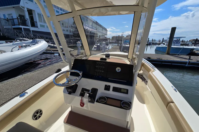 Slide: The Image of 2019 Scout 235 XSF boat dashboard at marina, clear sky, docked vessels. - 5