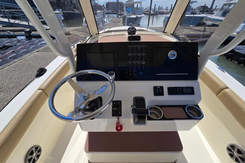 Slide: The Image of 2019 Scout 235 XSF boat helm with steering wheel and control panel at marina. - 6