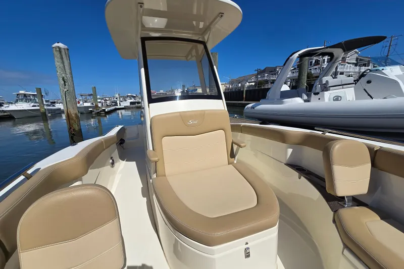 Slide: The Image of 2019 Scout 235 XSF boat interior with tan seating at marina. - 9