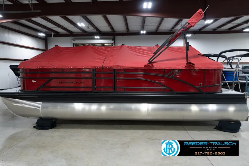 Slide: The Image of 2026 Bennington 22 SSR pontoon boat with red cover in indoor storage. - 50