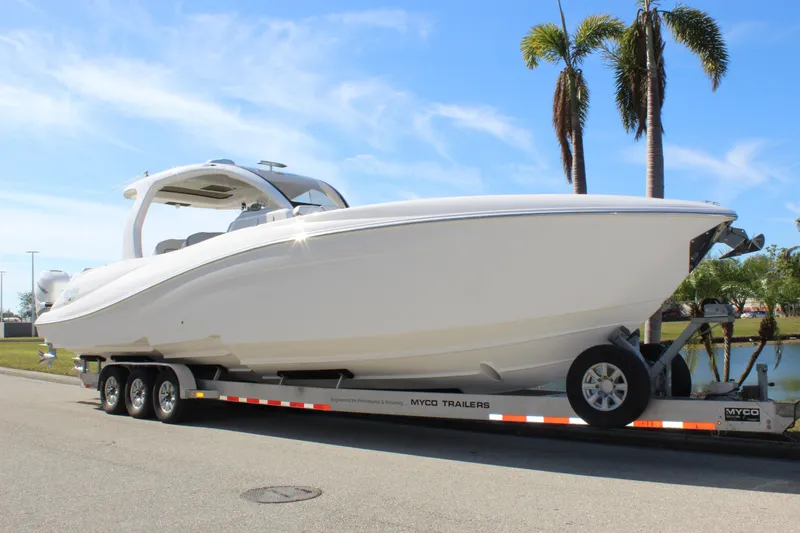 Slide: The Image of 2019 Deep Impact 399 Sport boat on trailer, parked near palm trees. - 1