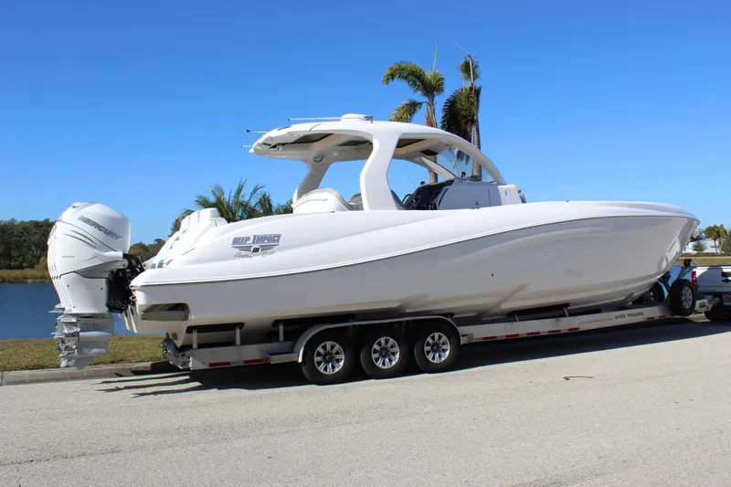 Slide: The Image of 2019 Deep Impact 399 Sport boat on trailer, parked near water, clear blue sky. - 11