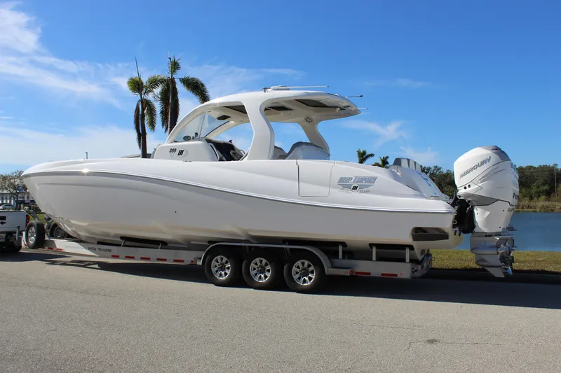 Slide: The Image of 2019 Deep Impact 399 Sport boat on trailer, parked near water with palm trees. - 12