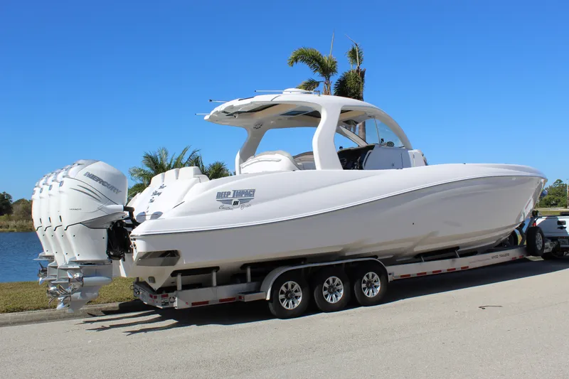 Slide: The Image of 2019 Deep Impact 399 Sport boat on trailer, parked near water, clear blue sky. - 13