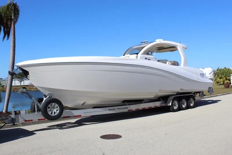 Slide: The Image of 2019 Deep Impact 399 Sport boat on trailer, parked near water under clear blue sky. - 2