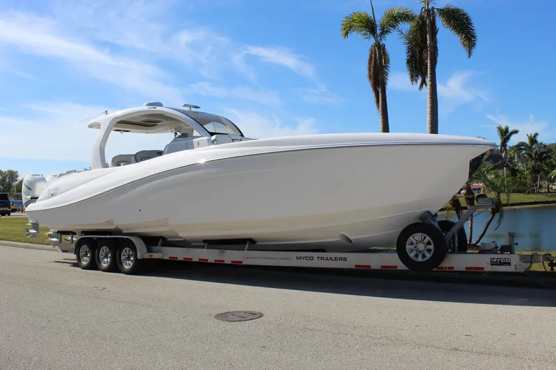 Slide: The Image of 2019 Deep Impact 399 Sport boat on trailer, parked near palm trees. - 3