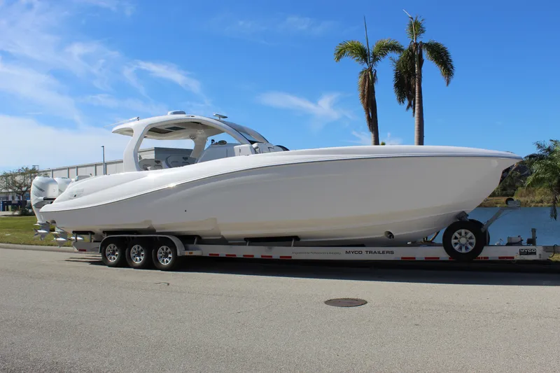 Slide: The Image of 2019 Deep Impact 399 Sport boat on trailer, parked near palm trees. - 5