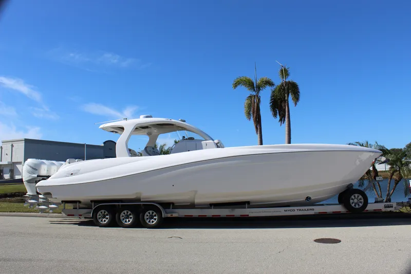 Slide: The Image of 2019 Deep Impact 399 Sport boat on trailer, parked near palm trees under clear blue sky. - 7