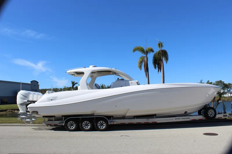 Slide: The Image of 2019 Deep Impact 399 Sport boat on trailer, parked near palm trees under clear blue sky. - 9