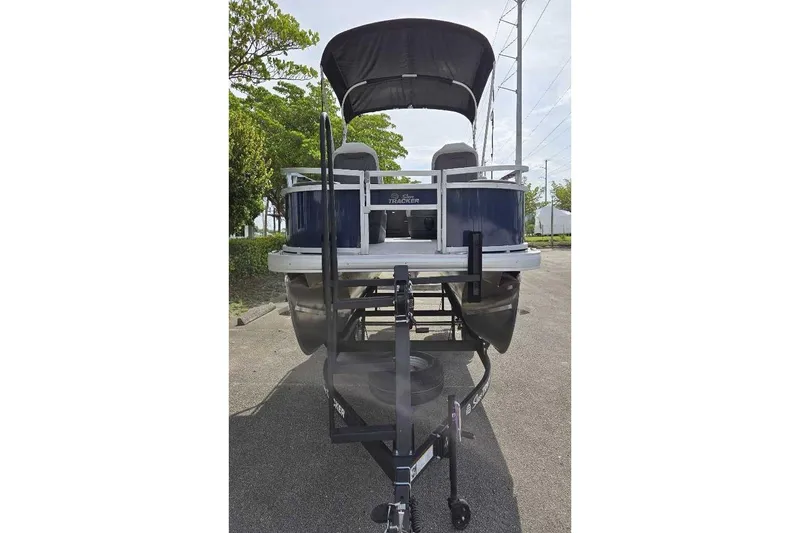 Slide: The Image of 2026 Sun Tracker Bass Buggy 18 DLX pontoon boat on trailer, parked outdoors. - 2