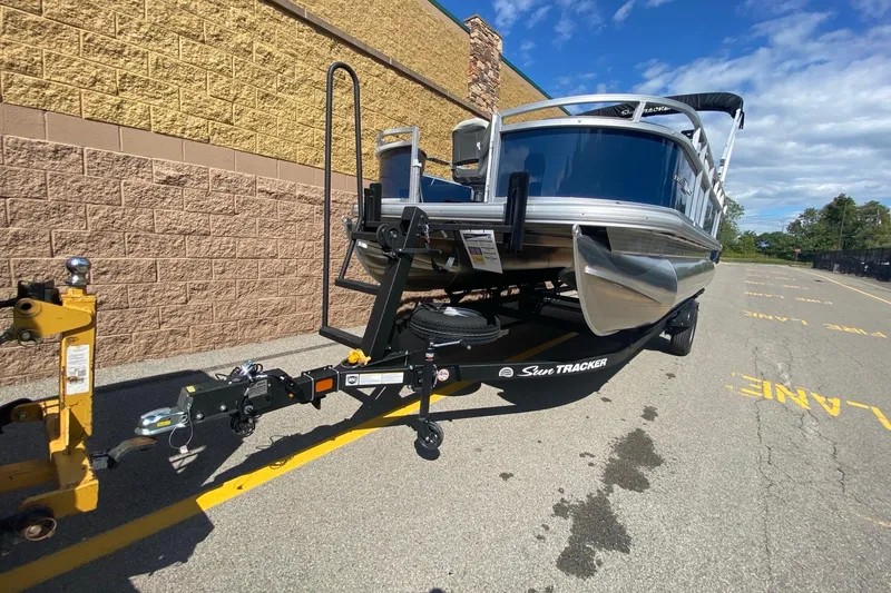 Slide: The Image of 2026 Sun Tracker Bass Buggy 18 DLX pontoon boat on trailer, parked outdoors. - 3