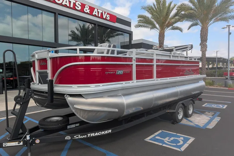 The Image of 2026 Sun Tracker SportFish 20 DLX pontoon boat on trailer, parked outside dealership. - 0