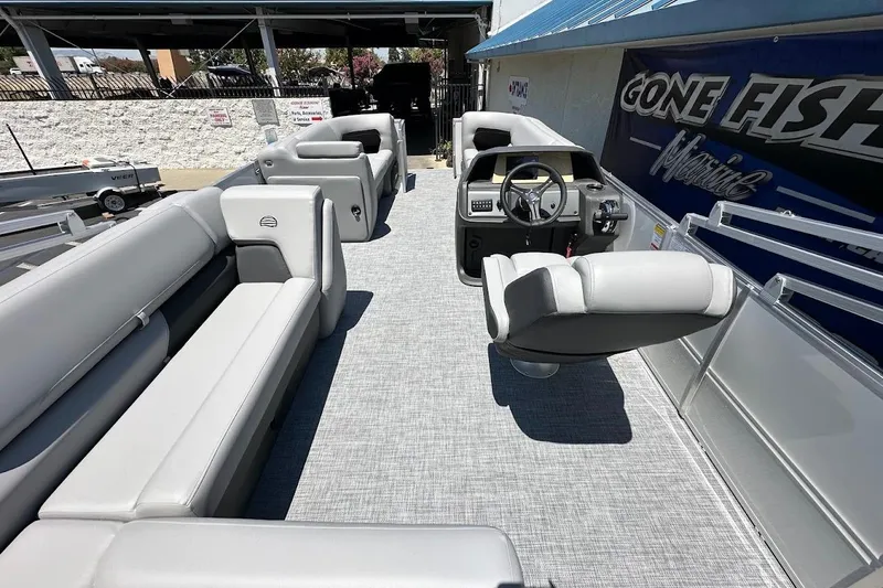 Slide: The Image of 2026 Sun Tracker Party Barge 20 DLX interior with gray seating and steering console. - 18