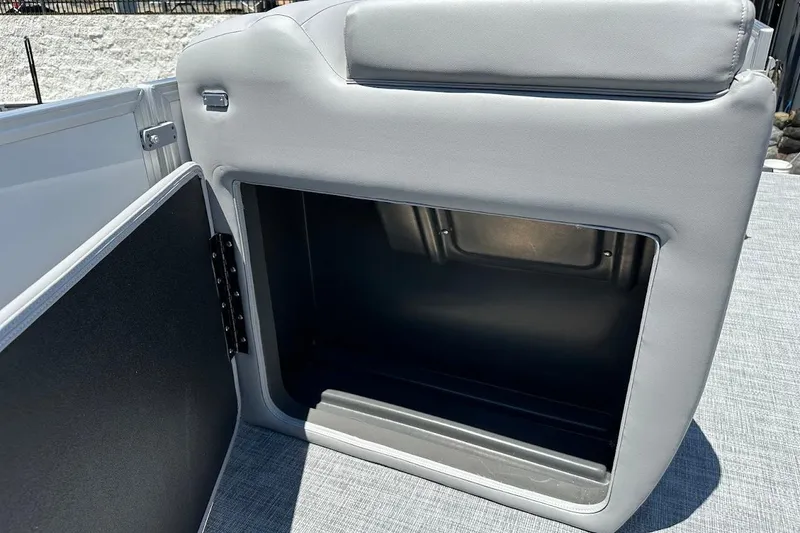 Slide: The Image of 2026 Sun Tracker Party Barge 20 DLX storage compartment with open door, gray upholstery. - 24