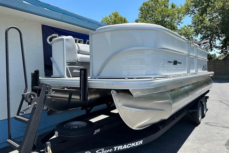 Slide: The Image of 2026 Sun Tracker Party Barge 20 DLX pontoon boat on trailer, parked outdoors. - 4