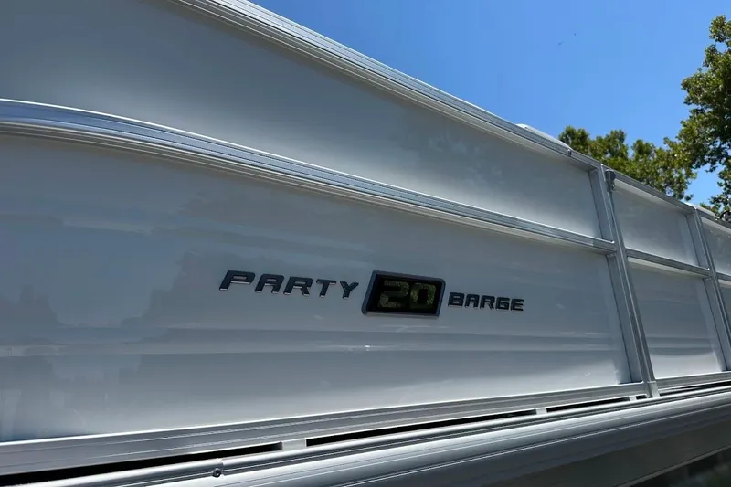 Slide: The Image of 2026 Sun Tracker Party Barge 20 DLX pontoon boat side view under clear blue sky. - 5