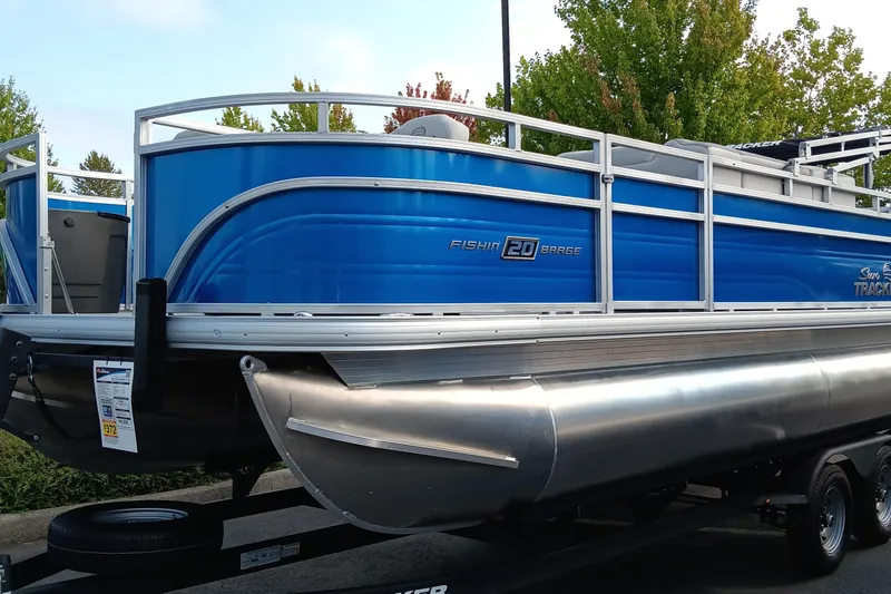 The Image of 2026 Sun Tracker Fishin' Barge 20 DLX pontoon boat in vibrant blue on trailer. - 0