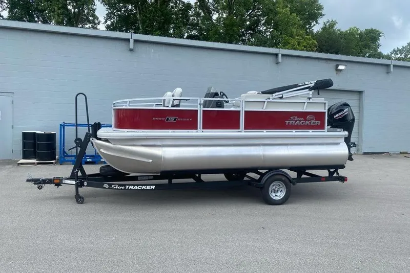 The Image of 2026 Sun Tracker Bass Buggy 16 XL Select pontoon boat on trailer, parked outdoors. - 0