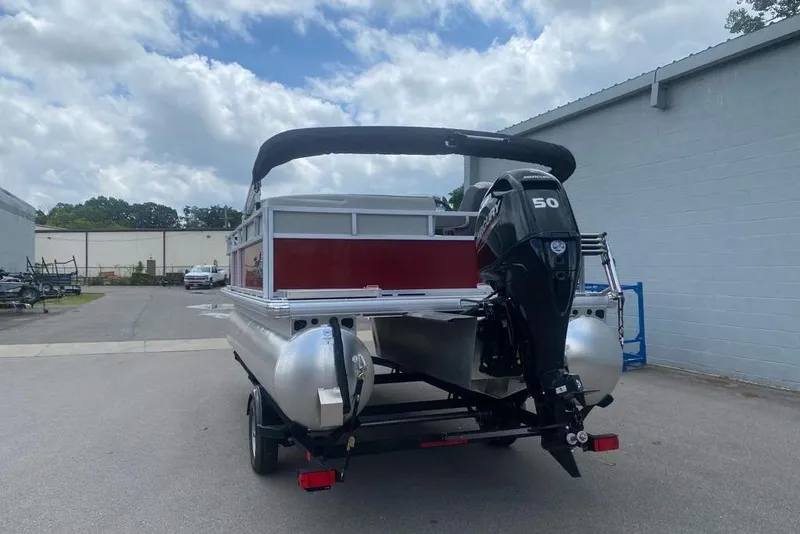 Slide: The Image of 2026 Sun Tracker Bass Buggy 16 XL Select pontoon boat with outboard motor, parked outdoors. - 79