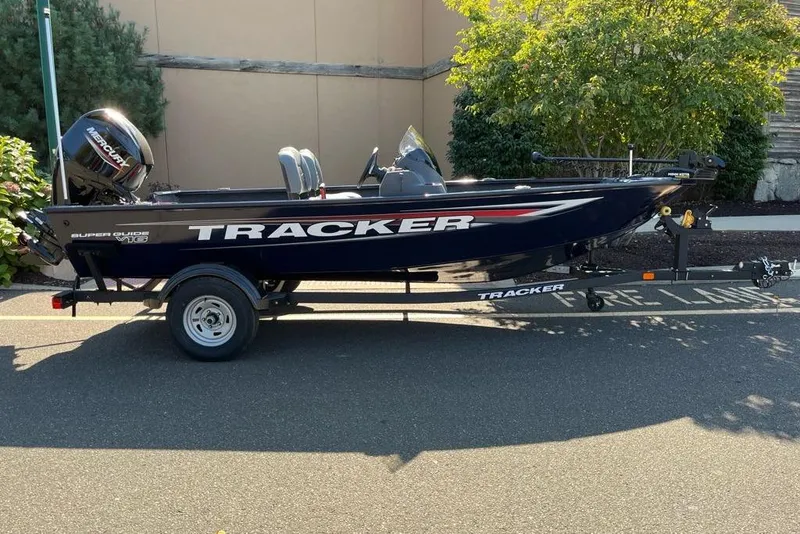 The Image of 2026 Tracker Super Guide V-16 SC boat on trailer, parked outdoors. - 0