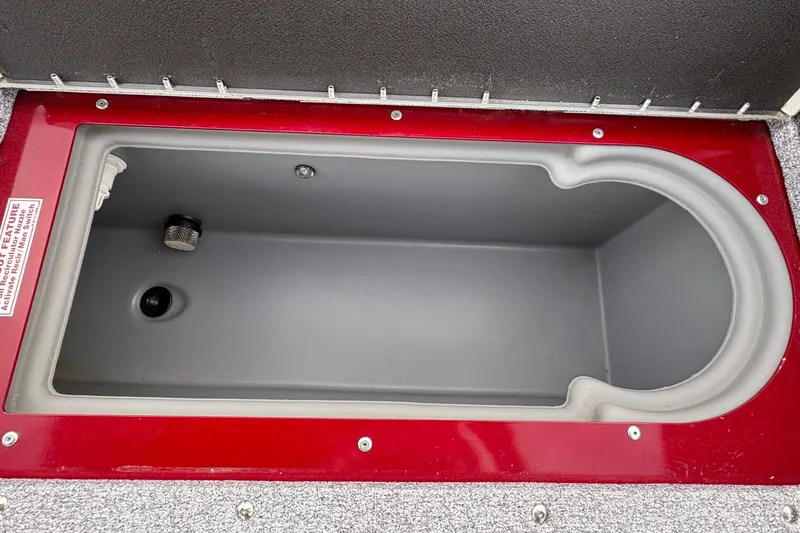 Slide: The Image of Open storage compartment in 2026 Tracker Targa V-19 Combo boat, featuring red trim and gray interior. - 77