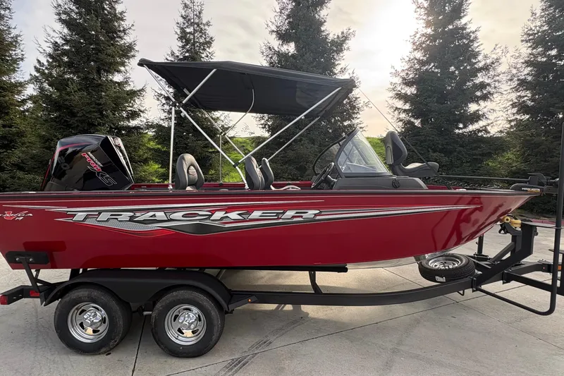 Slide: The Image of 2026 Tracker Targa V-19 Combo boat, red, on trailer, with canopy and outboard motor. - 86