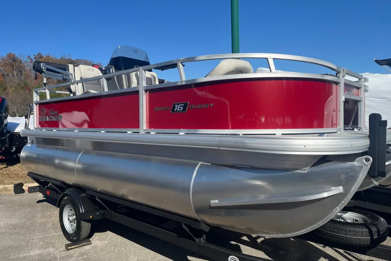 The Image of 2026 Sun Tracker Bass Buggy 16 XL Select pontoon boat on trailer, red and silver design. - 0